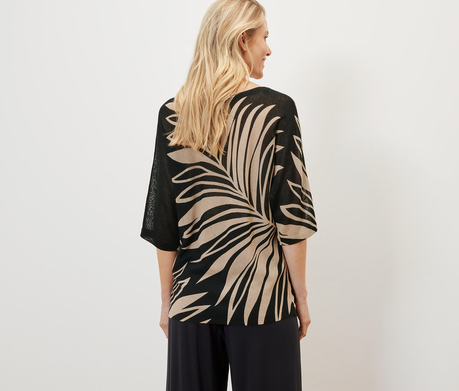 Nő visel nyomott mintás, finomkötésű pulóvert.