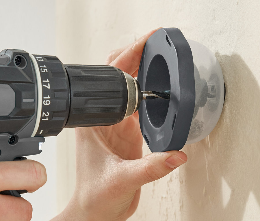 Egy személy fúr egy falat egy fúróval egy Bohrstaubfänger porfogón keresztül.