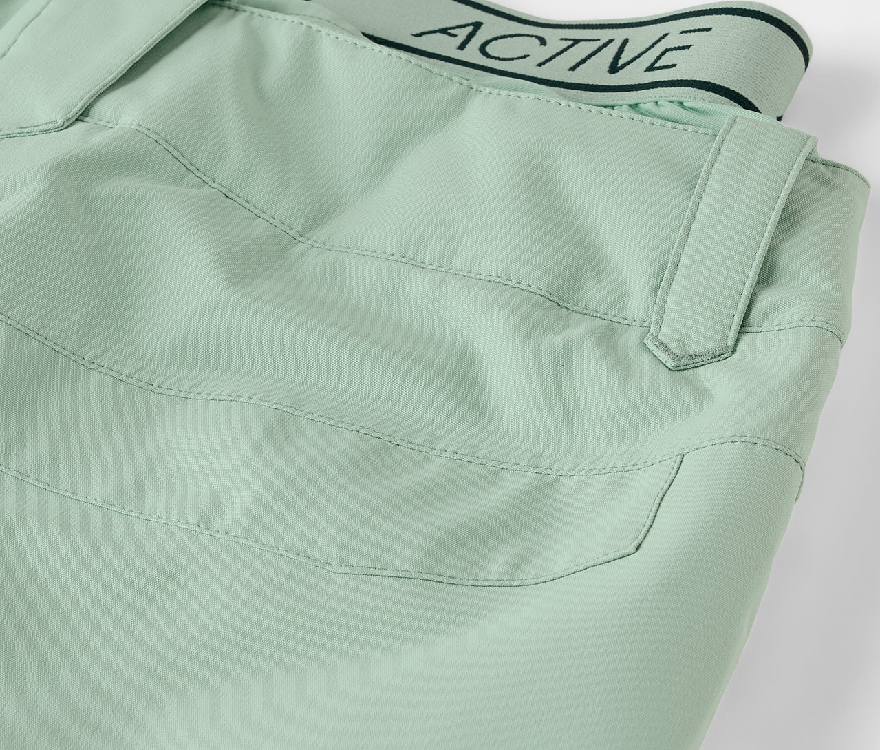 Világoszöld nadrág részlete zsebbel és ACTIVE feliratú derékpánttal.