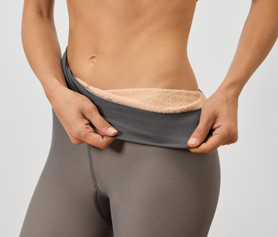 Nő tart egy szürke leggingset, aminek meleg bélése van.