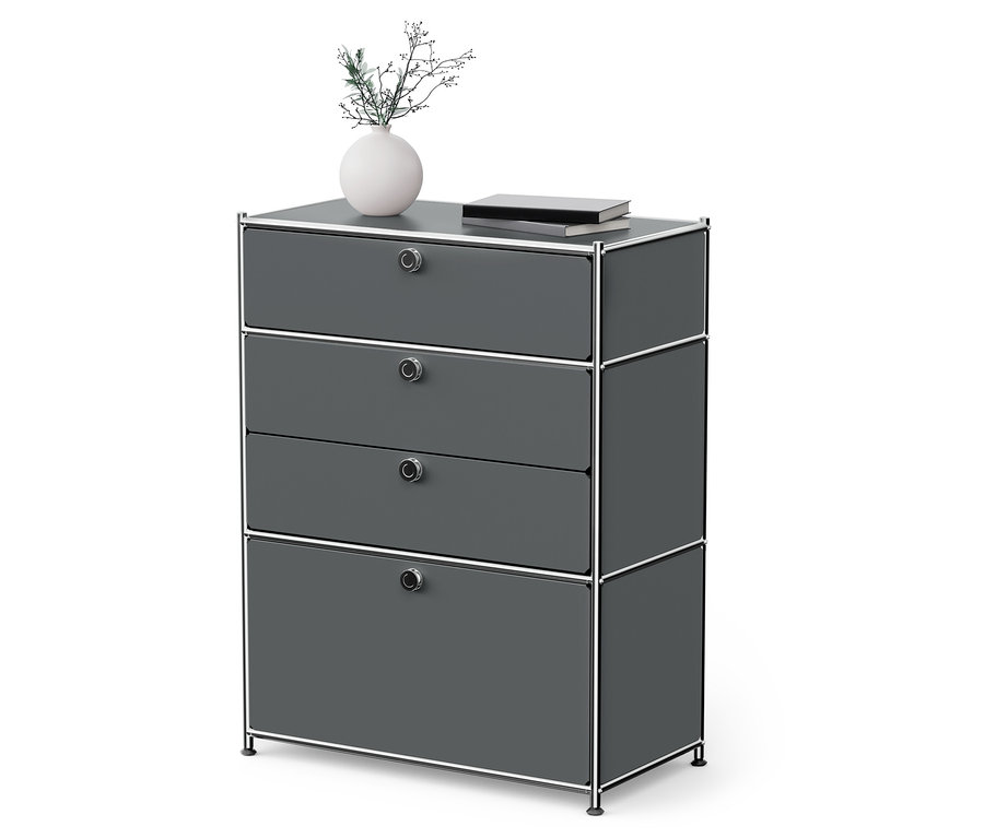 Szürke, négyfiókos komód króm vázzal. A komódon egy váza virág és egy könyv található.