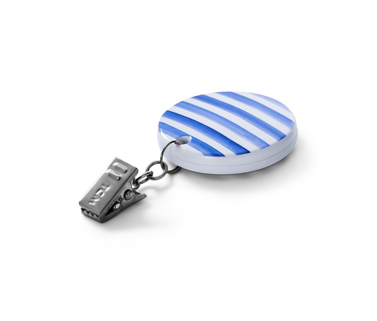 Egyetlen asztalterítő-leszorító részletfotója. A leszorító kék-fehér csíkos, ezüst színű klippel.