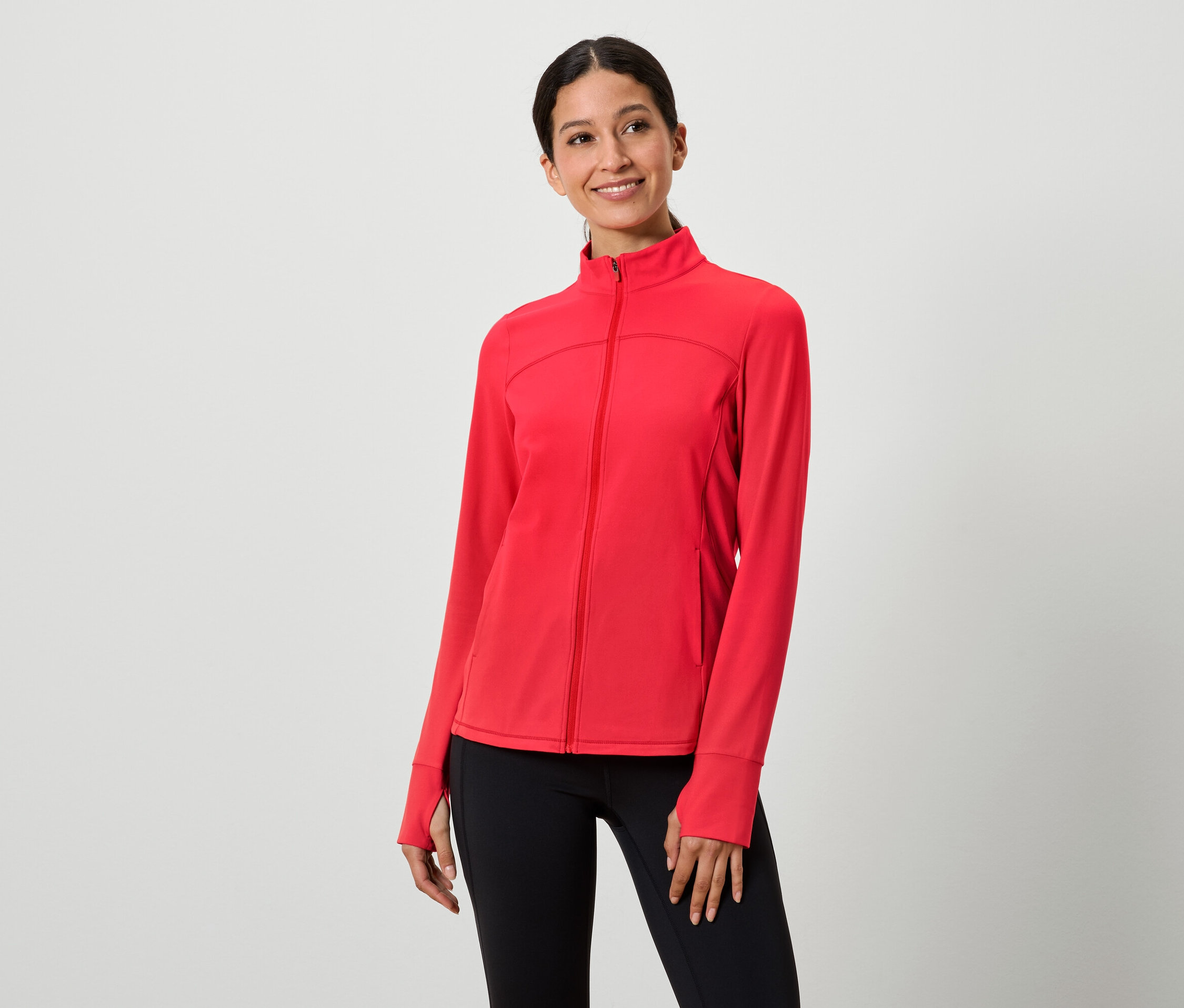 Nő visel piros cipzáras kabátot és fekete leggingset.