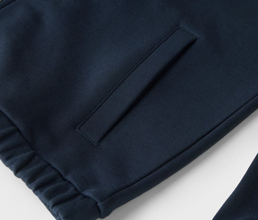 Egy sötétkék, cipzáros, zsebes pulóver közeli képe.