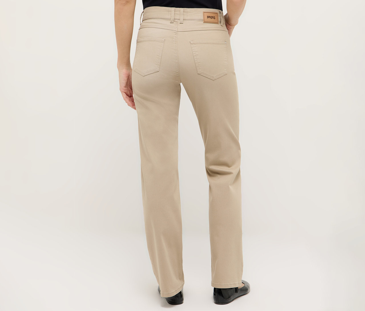 Egy bézs nadrágot és fekete cipőt viselő nő hátulnézete.