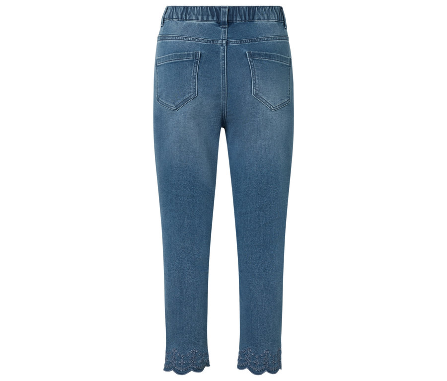 Kék farmernadrág hátulnézetének közeli képe, rugalmas derékrésszel és dekoratív csipkével az alján.