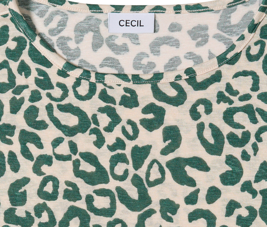 Közelkép egy bézs színű CECIL rövid ujjú felsőről, zöld leopárdmintával. A CECIL márkajelzés a nyakkivágásnál látható.