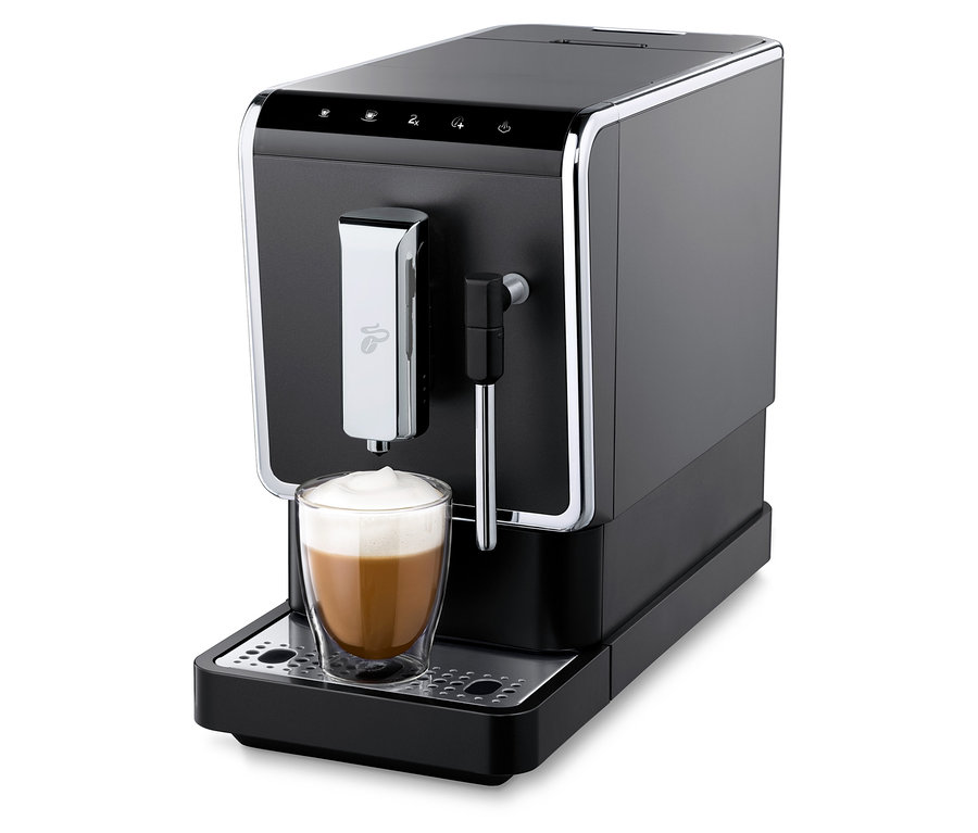 Egy antracit színű »Esperto Latte« Tchibo automata kávéfőző italt készít egy pohárba.