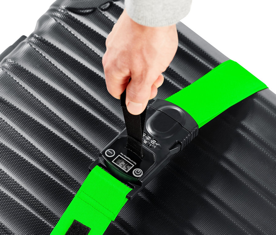 Egy kéz egy zöld 3 az 1-ben bőröndpántot tart egy fekete bőröndön.