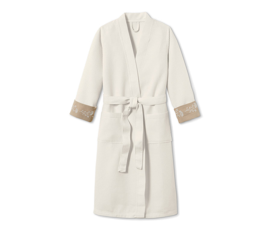 Fehér női fürdőköpeny virágmintával a mandzsettákon.