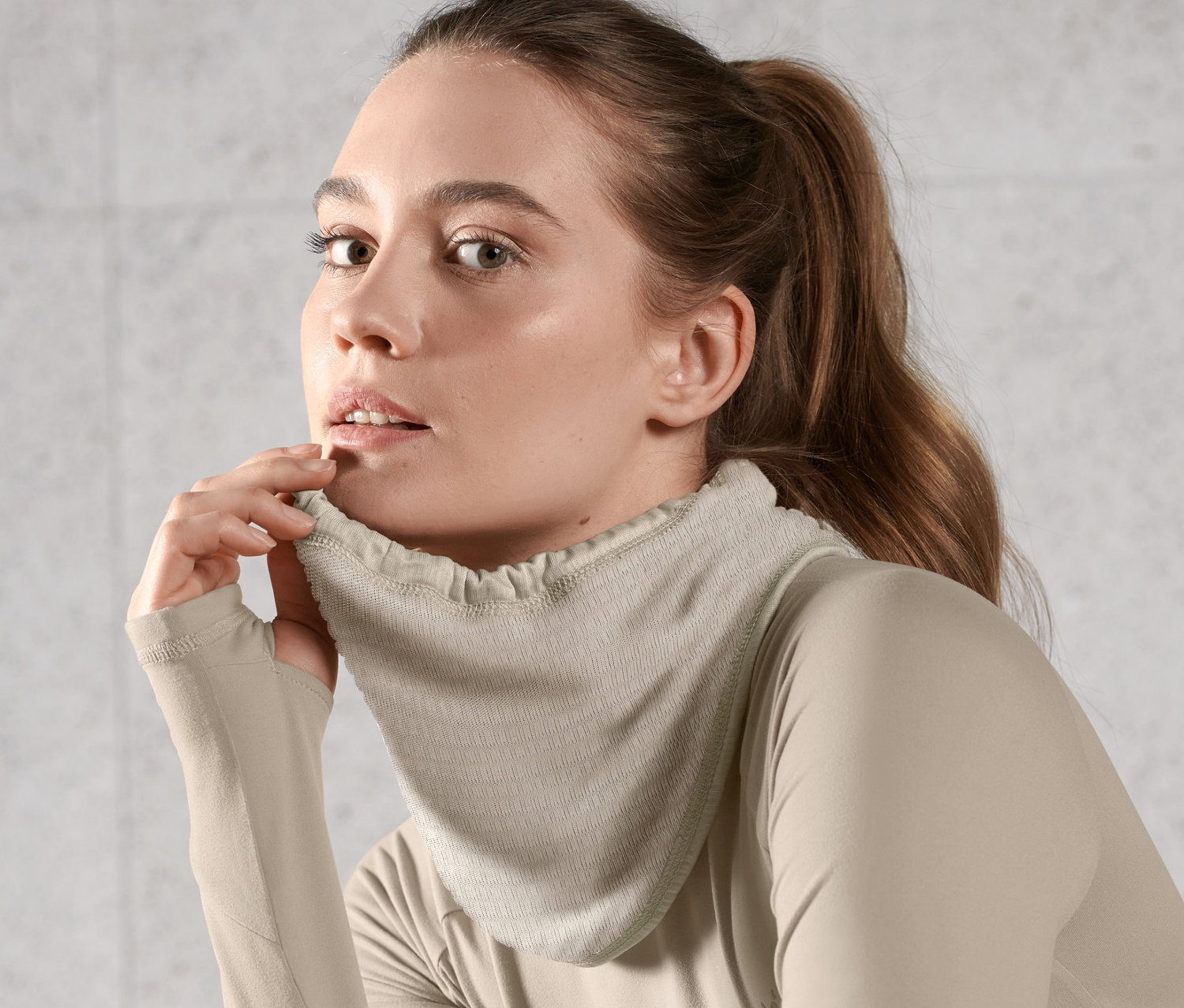 Nő visel világosbarna multifunkcionális kendőt és hosszú ujjú felsőt.