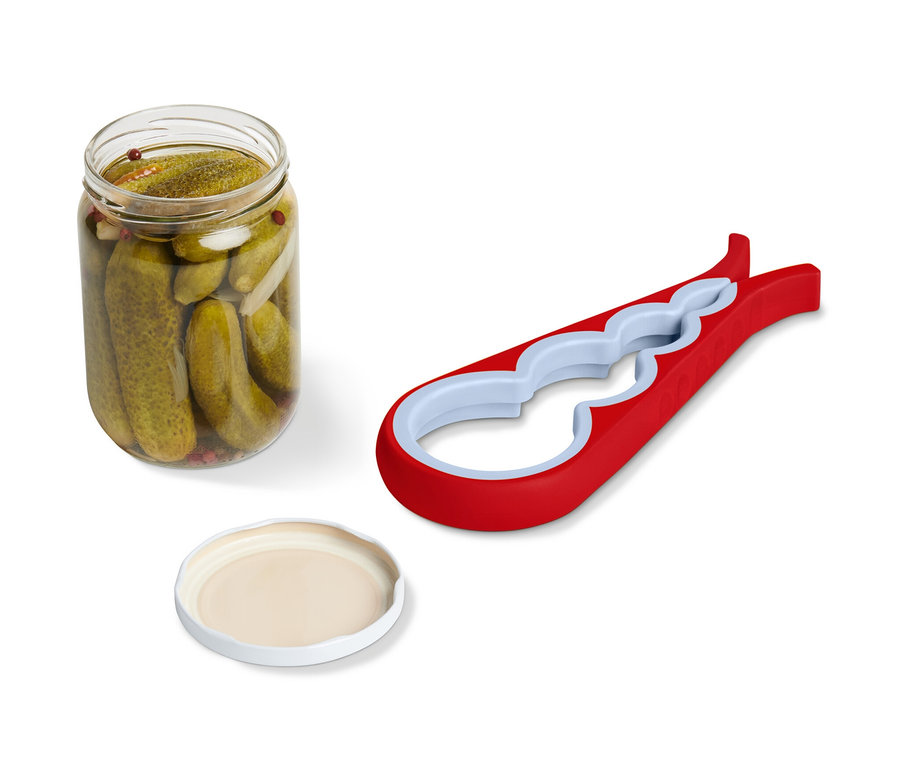 Egy üveges uborka, egy fedő és egy piros üveg- és palacknyitó fekszik egymás mellett.