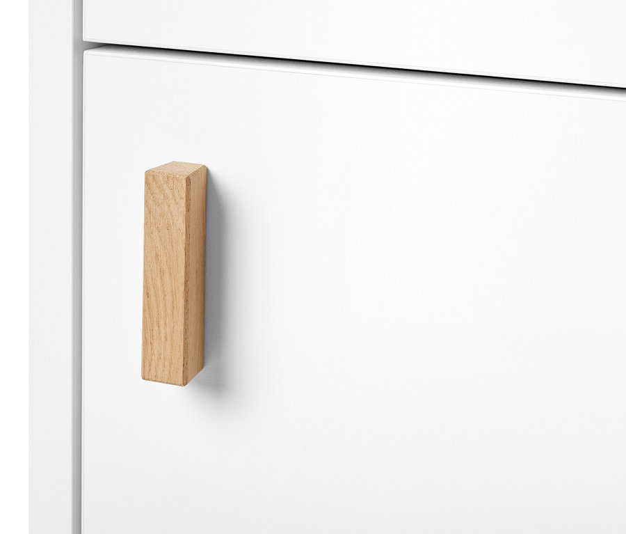 Egy keskeny, fehér fürdőszobai magas szekrény részlete fa fogantyúval.