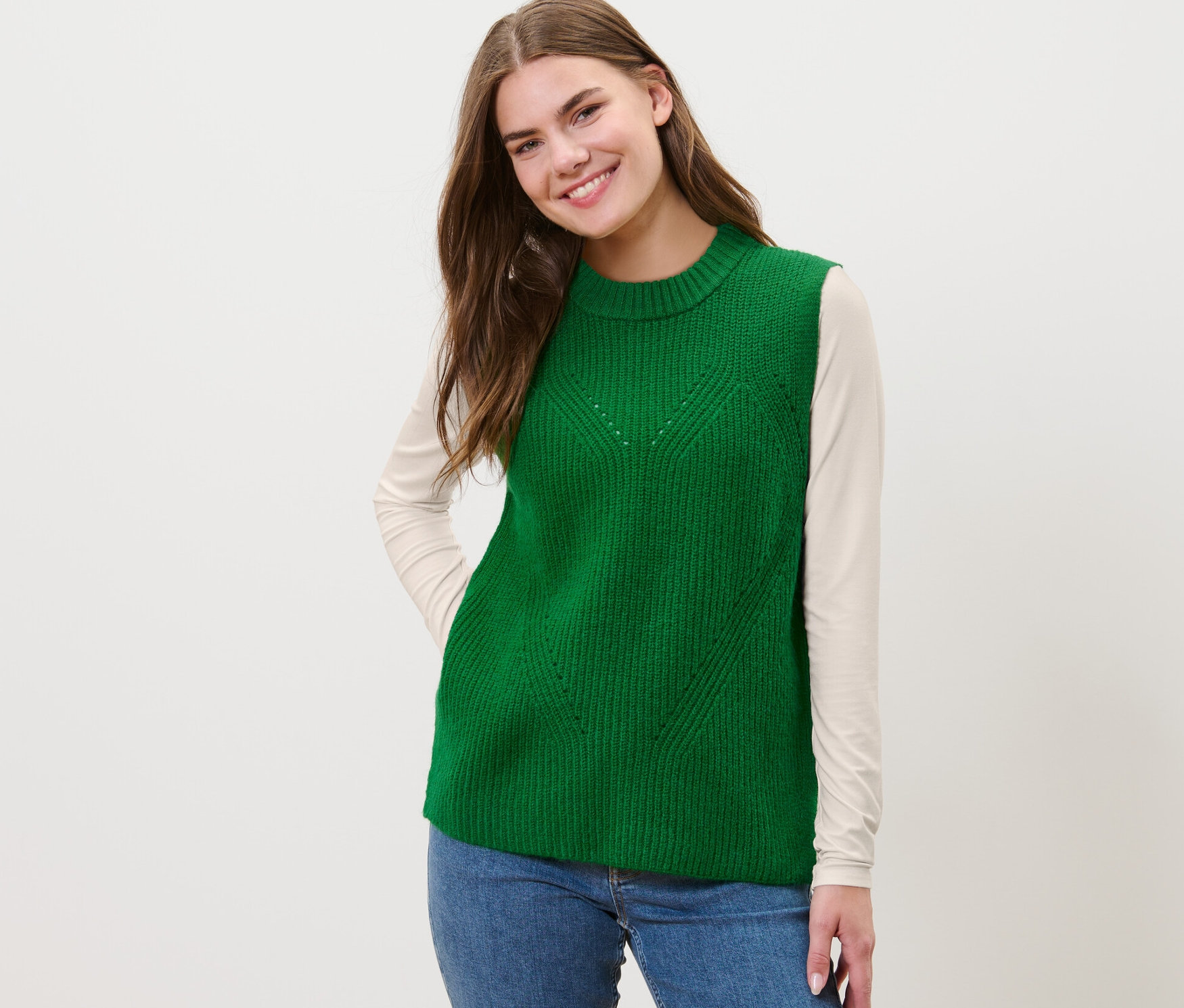 Nő visel egy zöld kötött mellényt.