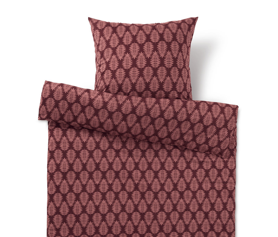 Ágynemű és párna levélmintával piros árnyalatokban.