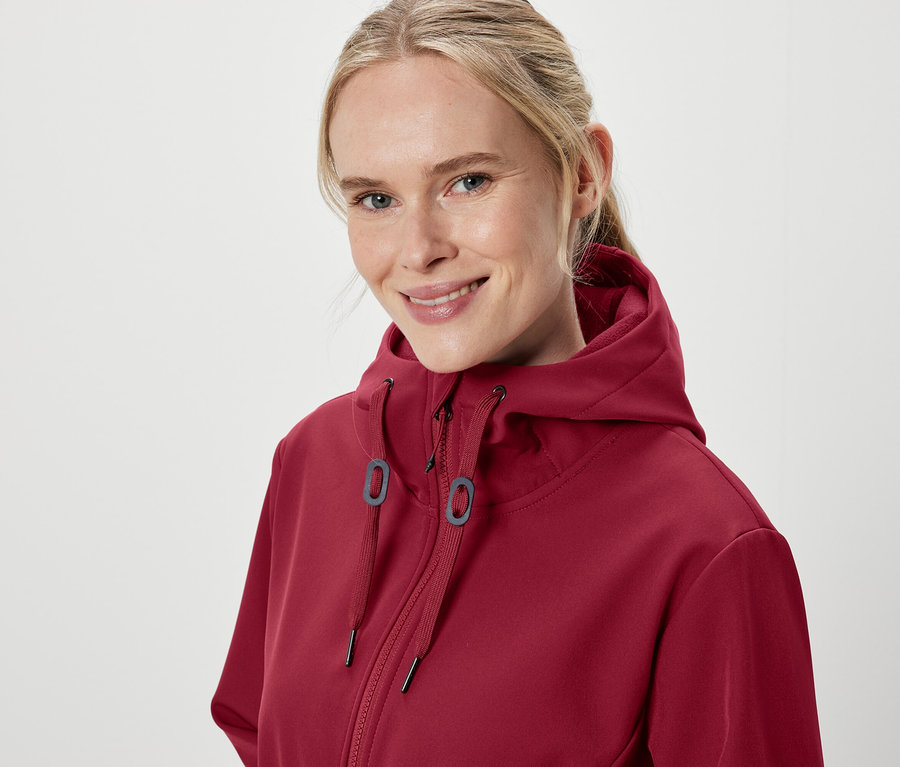 Egy mosolygó nő portréja bordó kapucnis pulóverben.