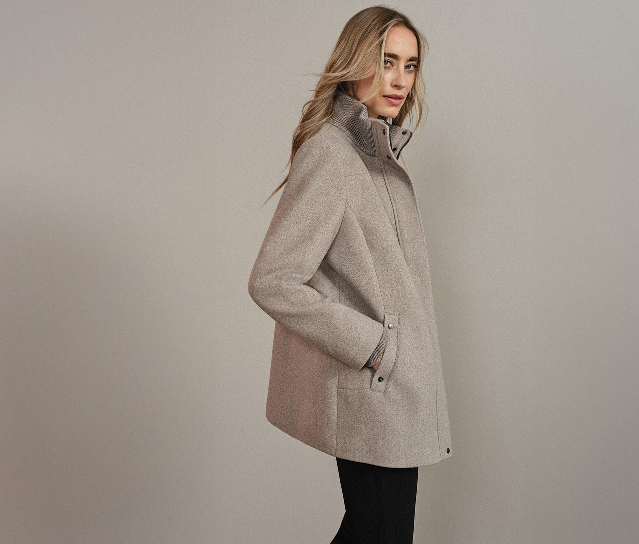 Egy nő bézs Street One rövid kabátban, kezével a zsebében.