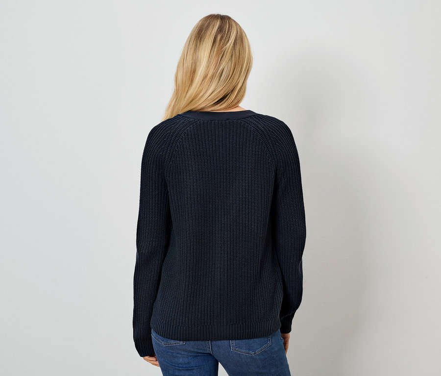 Hátulról látható nő sötétkék pulóvert és farmert visel.