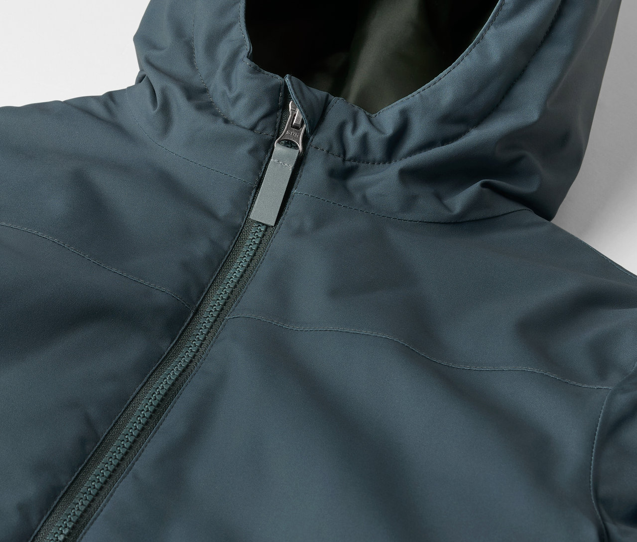 Egy gyermek téli parka részlete kapucnival és cipzárral.