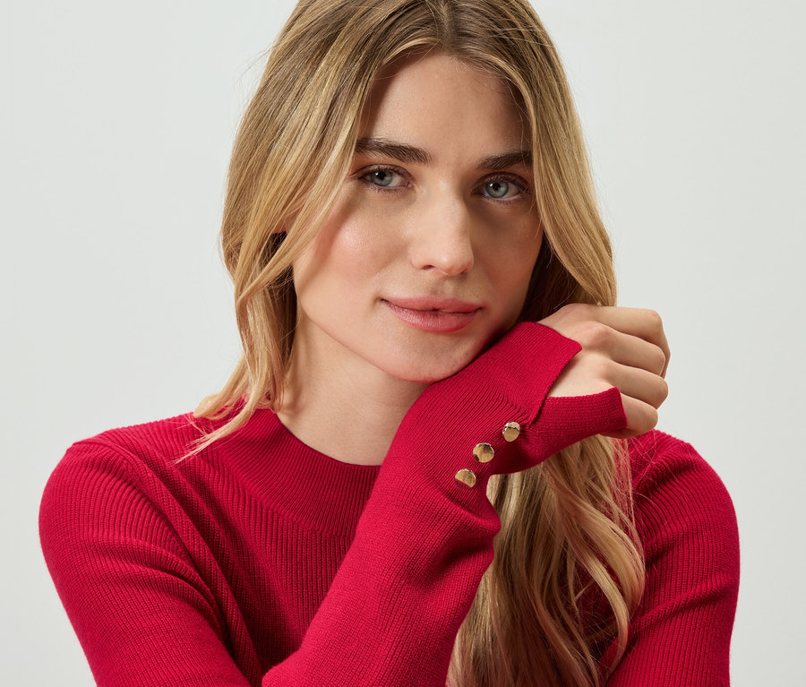 Egy szőke nő portréja piros pulóverben.