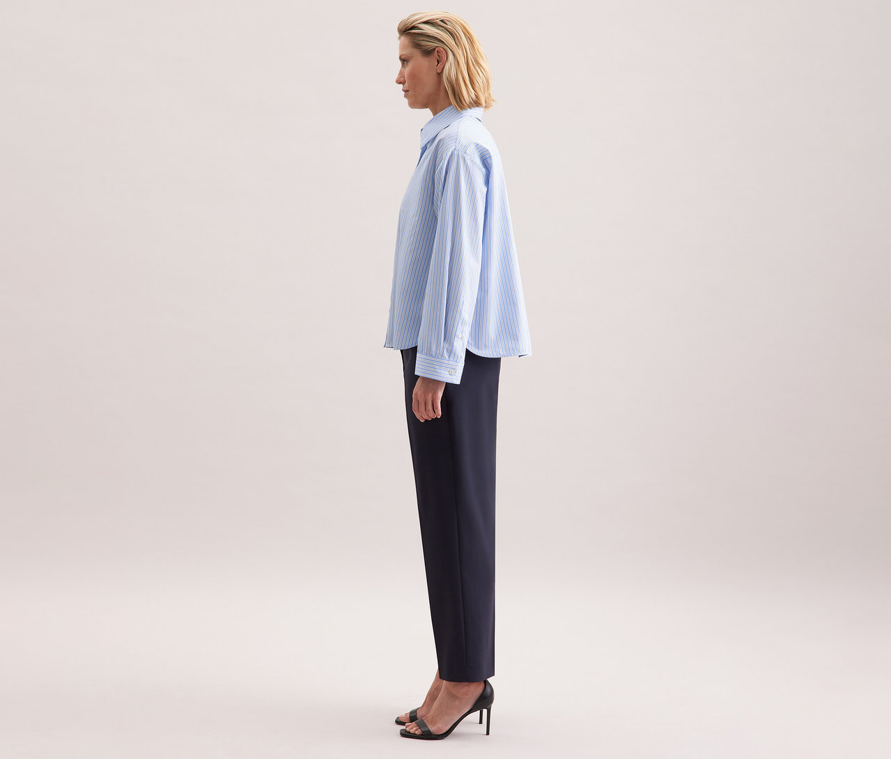 Profilból látható nő Seidensticker túlméretezett ingblúzban és sötét nadrágban.