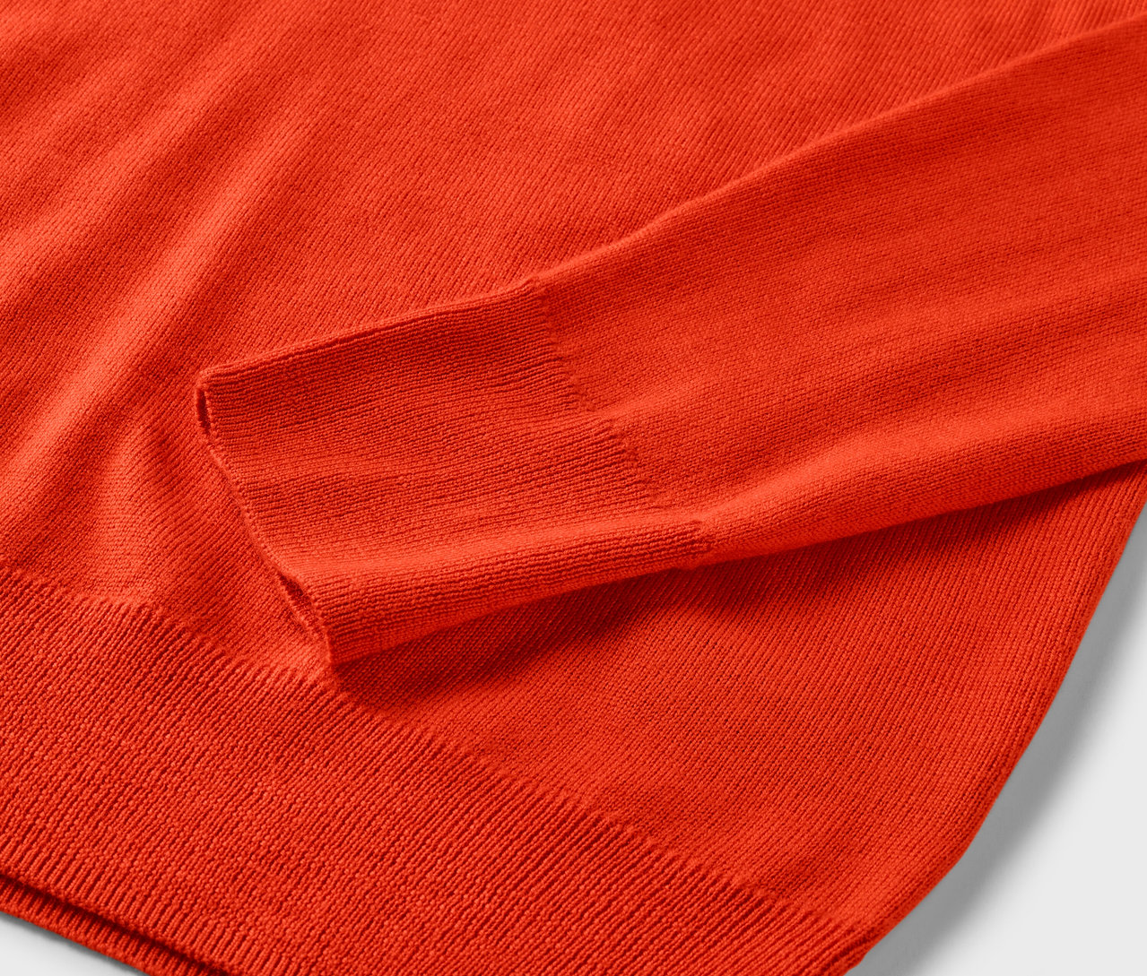 Közelkép a narancssárga Mernio kötött pulóverről.