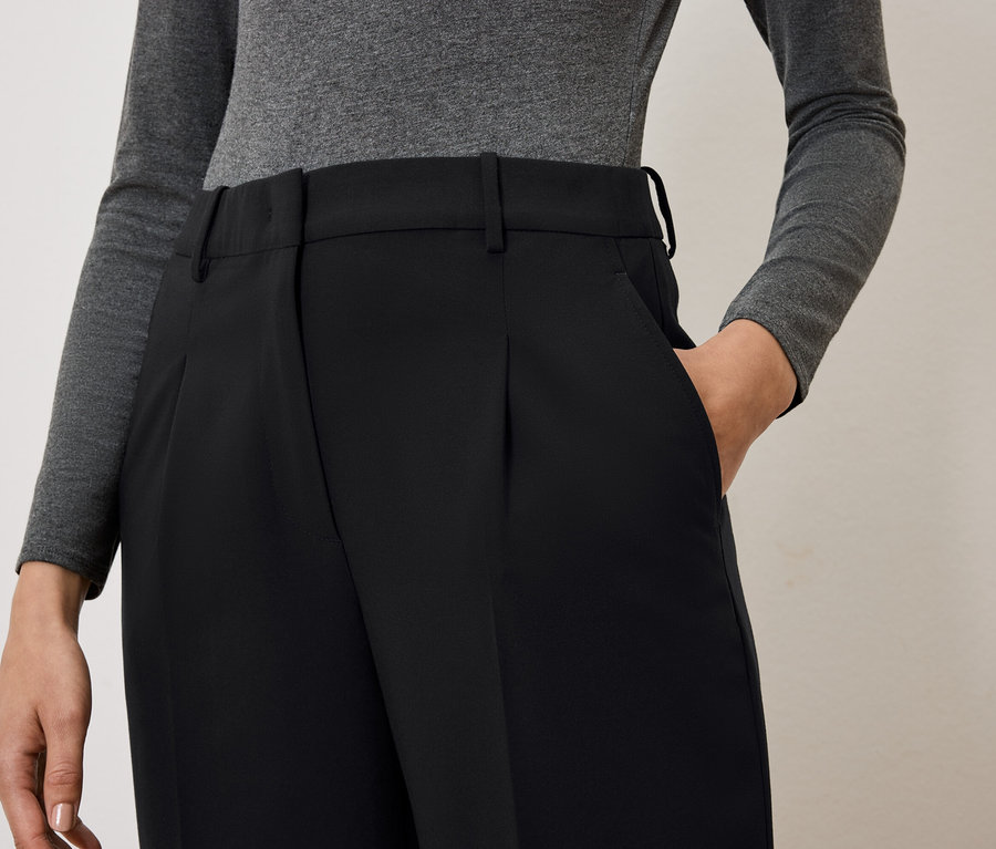 Nő keze a fekete nadrág zsebében.