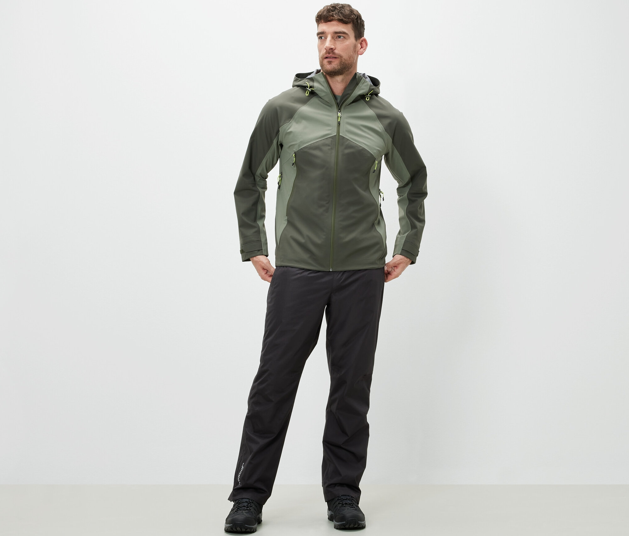 Férfi áll, high-tech esőnadrágot és kabátot visel.