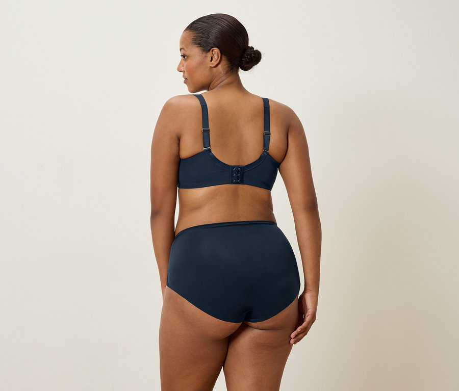 Egy sötét hajú nő hátulról látható, sötétkék melltartót és hozzáillő bugyit visel.