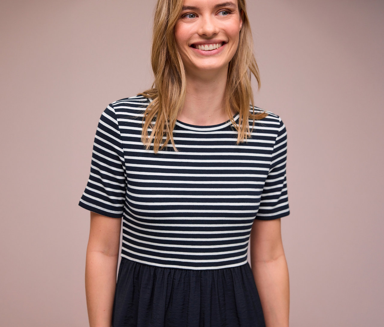 Mosolygó nő kék-fehér csíkos Street One ruhát visel.