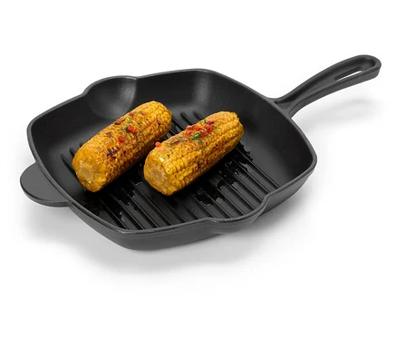 Két fűszerezett kukoricacső fekszik egy fekete grillserpenyőben.