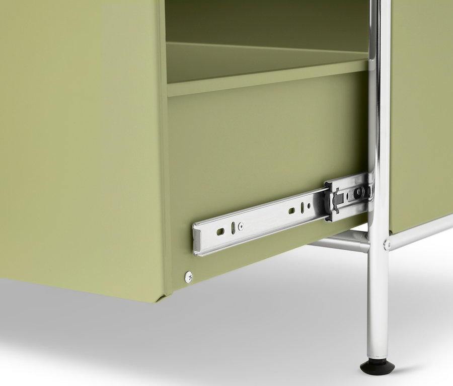 Egy világoszöld szekrény közeli képe ezüst lábakkal és részben nyitott fiókkal.