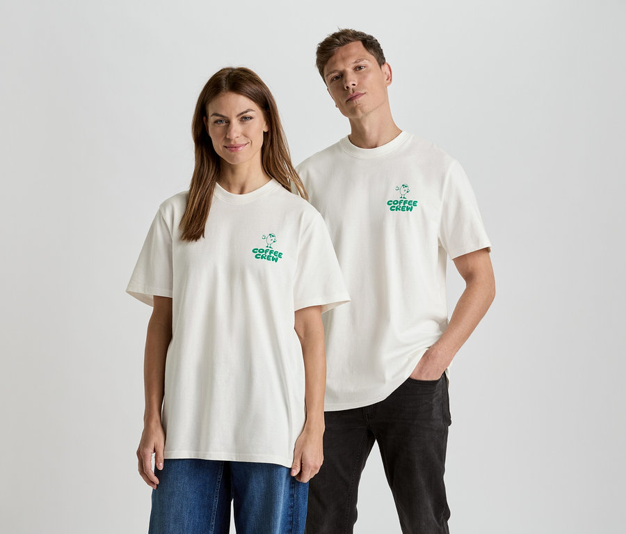 Egy nő és egy férfi áll egymás mellett, "Coffee Crew" feliratú, egymáshoz illő pólót viselnek.