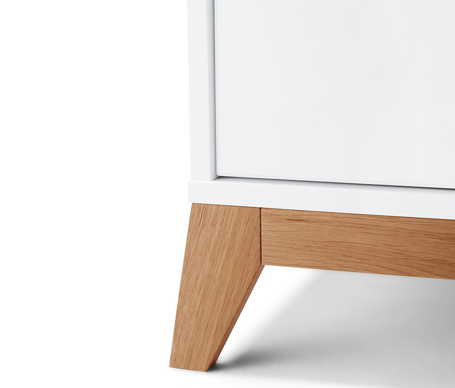 Egy fehér pelenkázó komód részlete fa lábakkal.