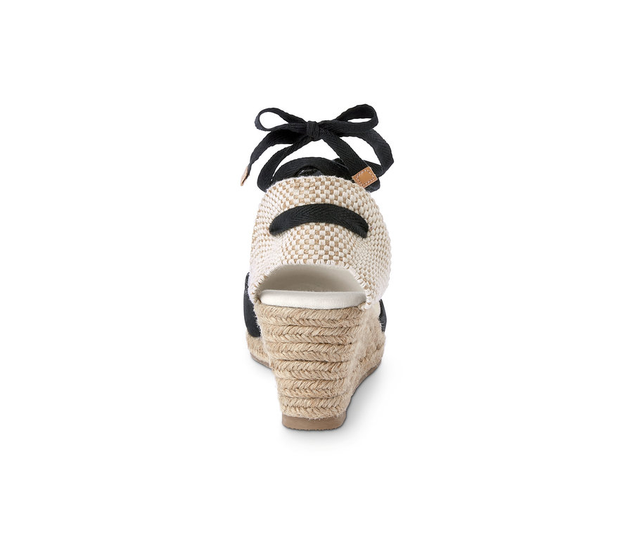 Egy fekete szalaggal és bézs színű, kötött sarokkal ellátott, éktalpú espadrilles hátulnézetének részlete.