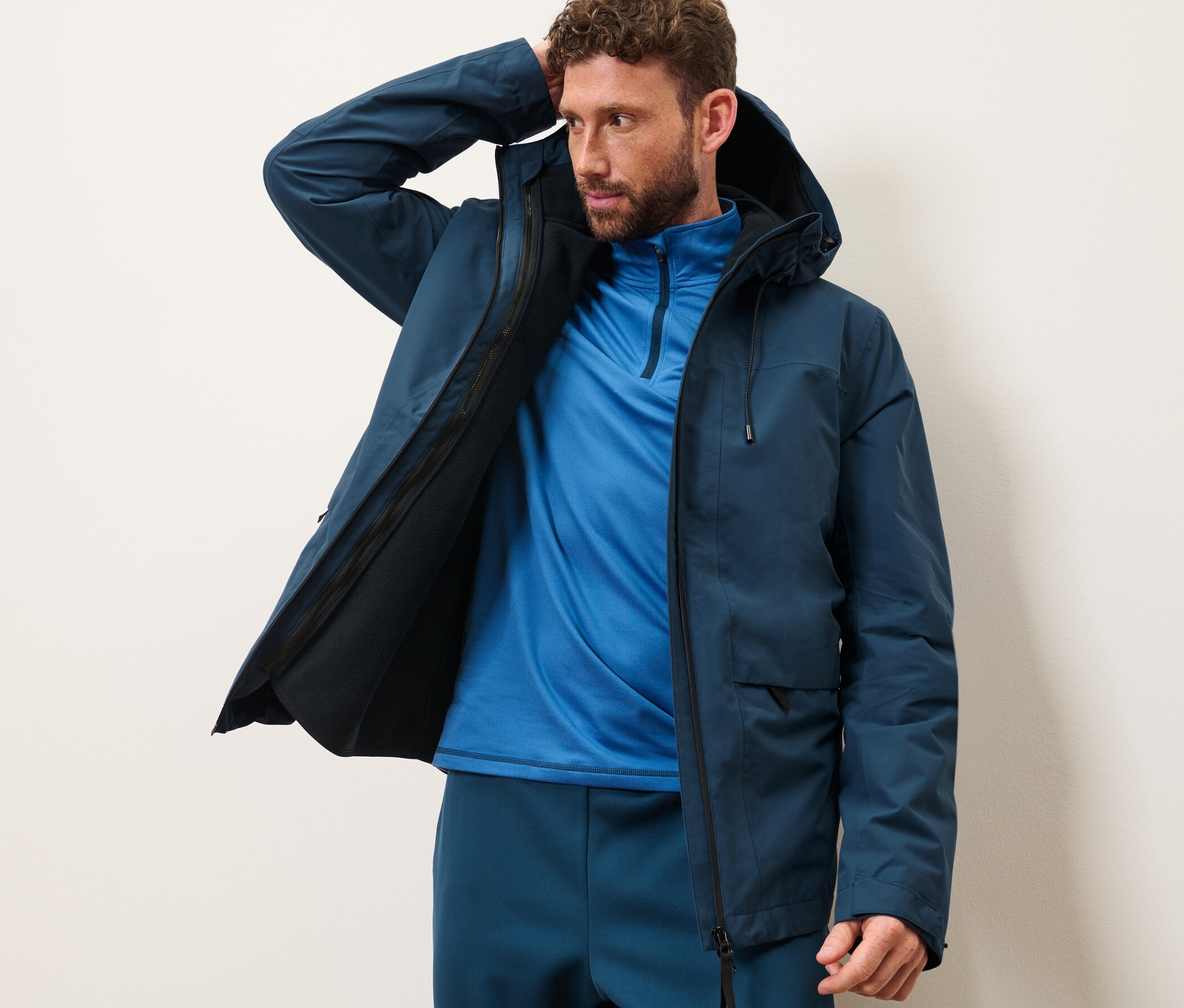 Férfi pózol sötétkék túrakabátban.