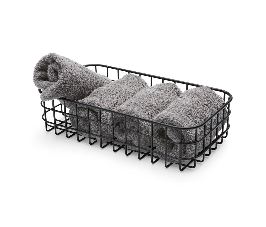 Négy szürke törölköző van szépen feltekerve egy fekete fűszertartó kosárban.