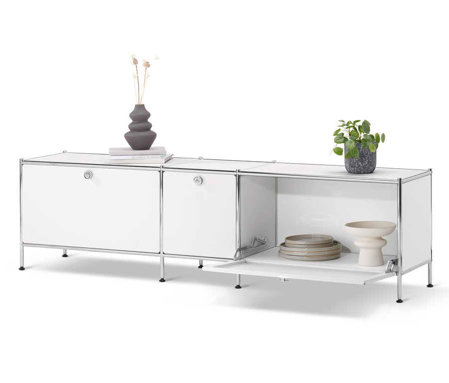 Fehér »CN3« alacsony komód, 3 ajtós. A komódon váza, könyv és cserepes virág van.