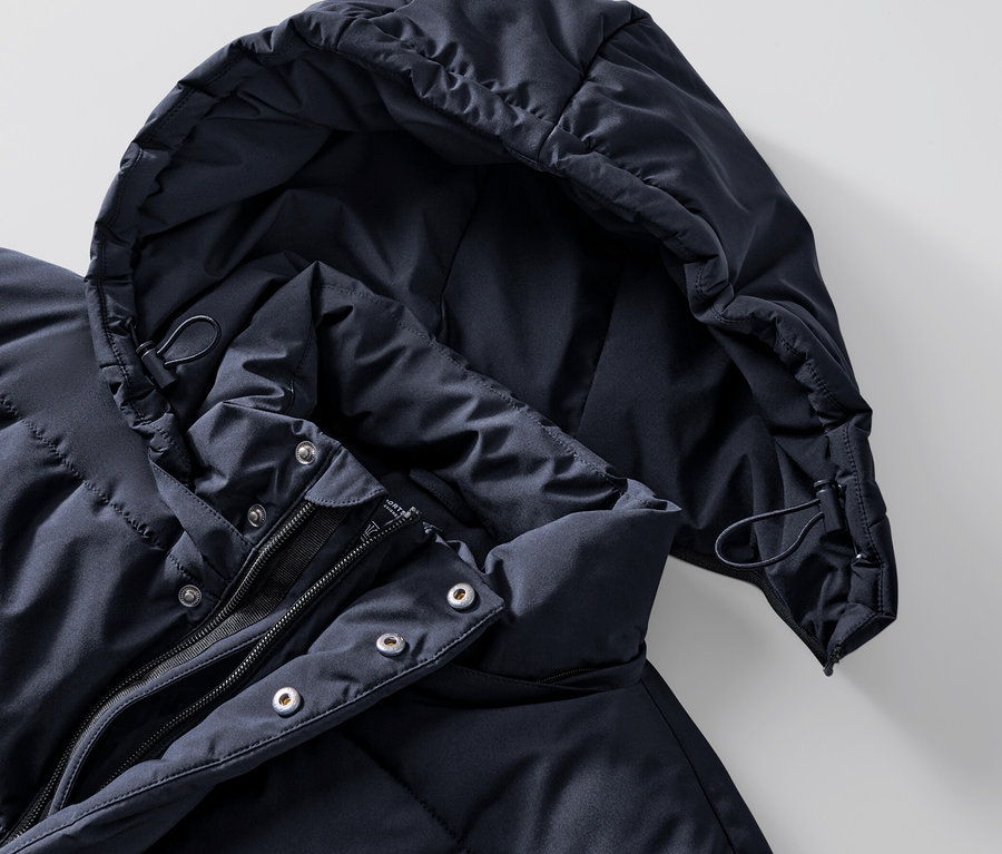 Egy sötétkék, steppelt parka kabát részletfotója.