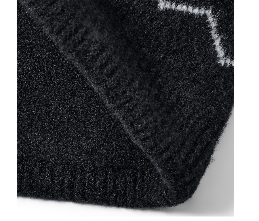 Egy fekete, mintás, polárbéléssel ellátott kötött csősál részlete.