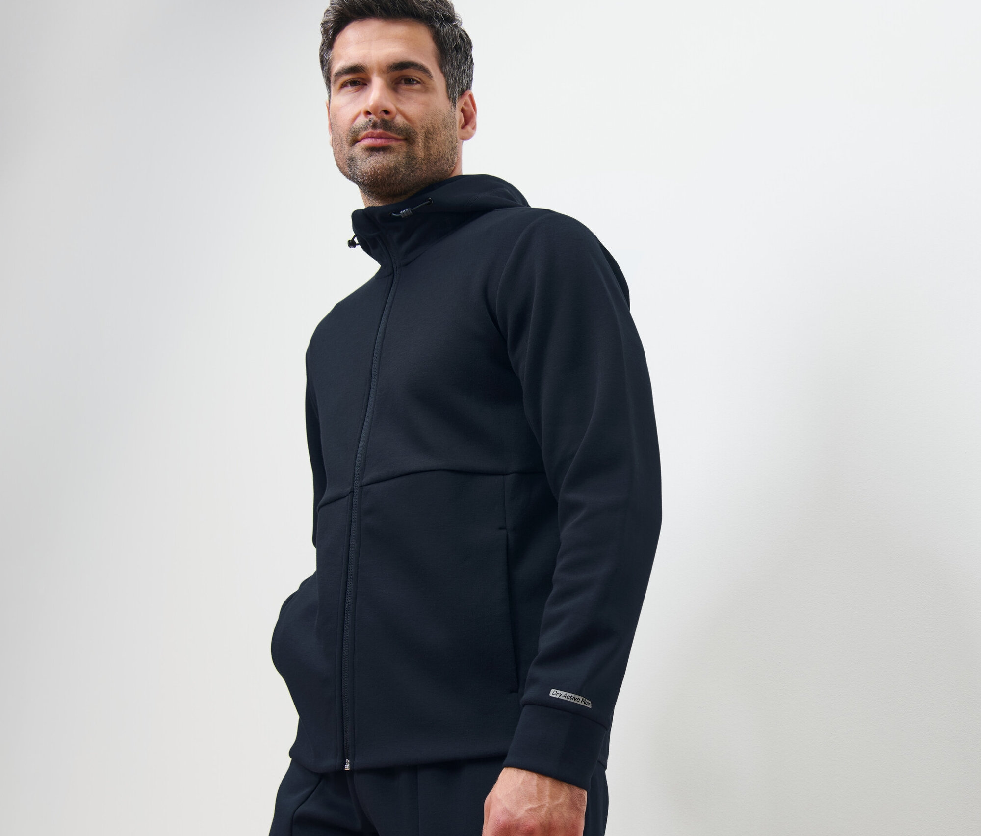 Férfi sötétkék funkcionális szabadidőfelsőben pózol.