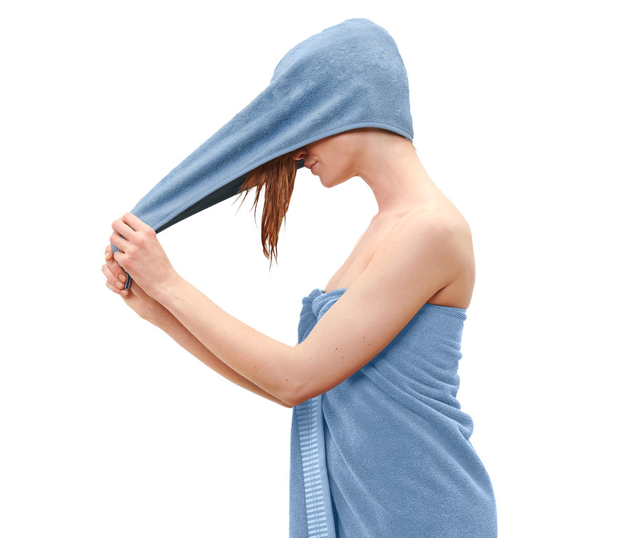 Egy nő kék turbán alakú törölközőt teker a fejére.