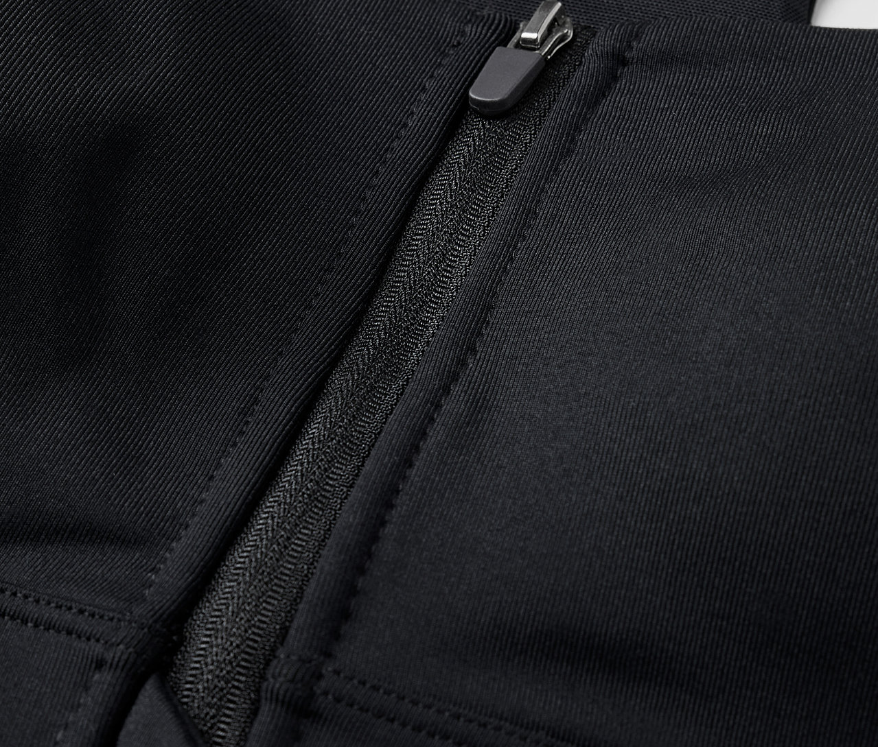 Egy fekete, elöl cipzáros sportmelltartó részlete.