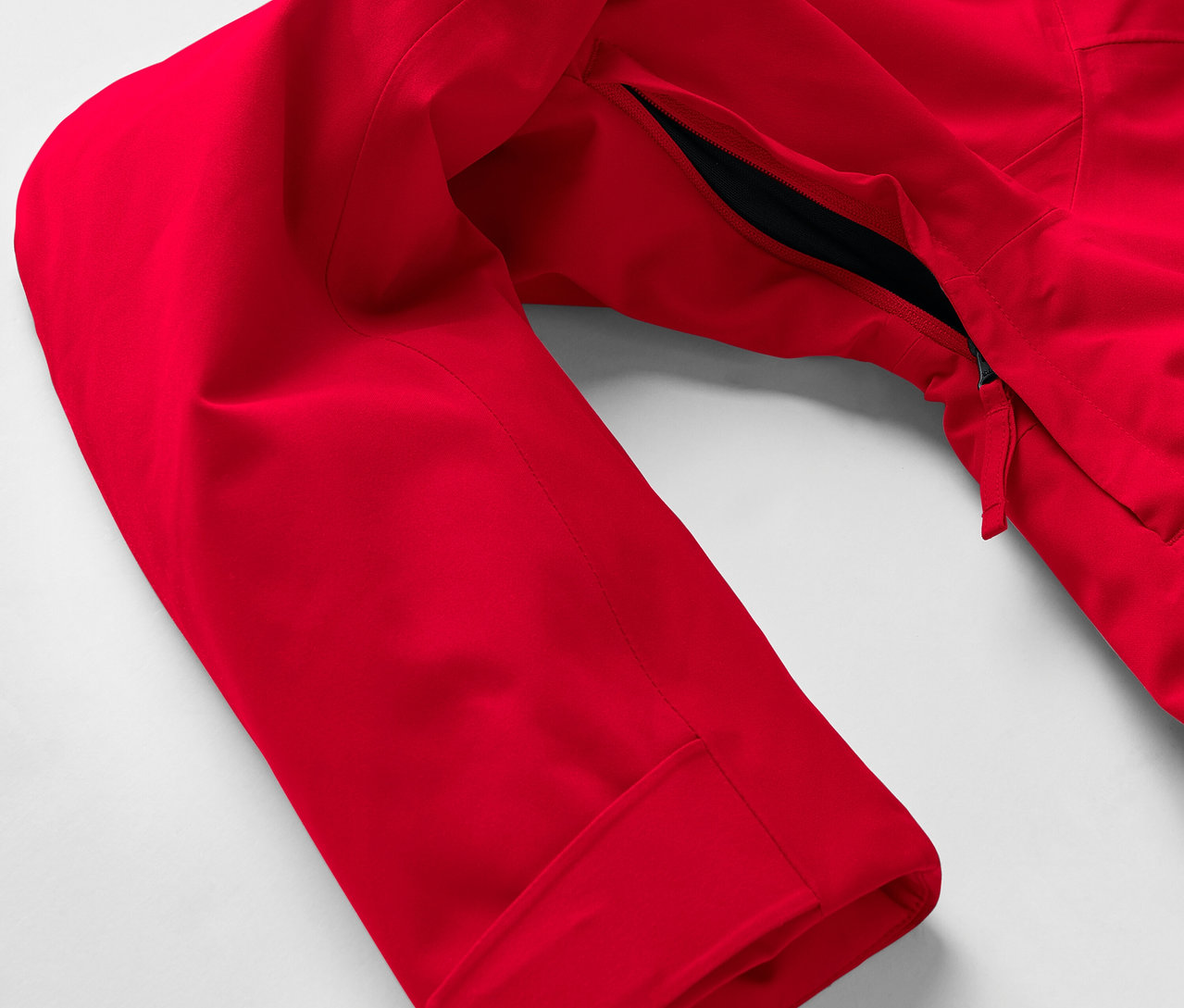 Egy piros kabát részlete, ujjjal és cipzáras zsebbel.