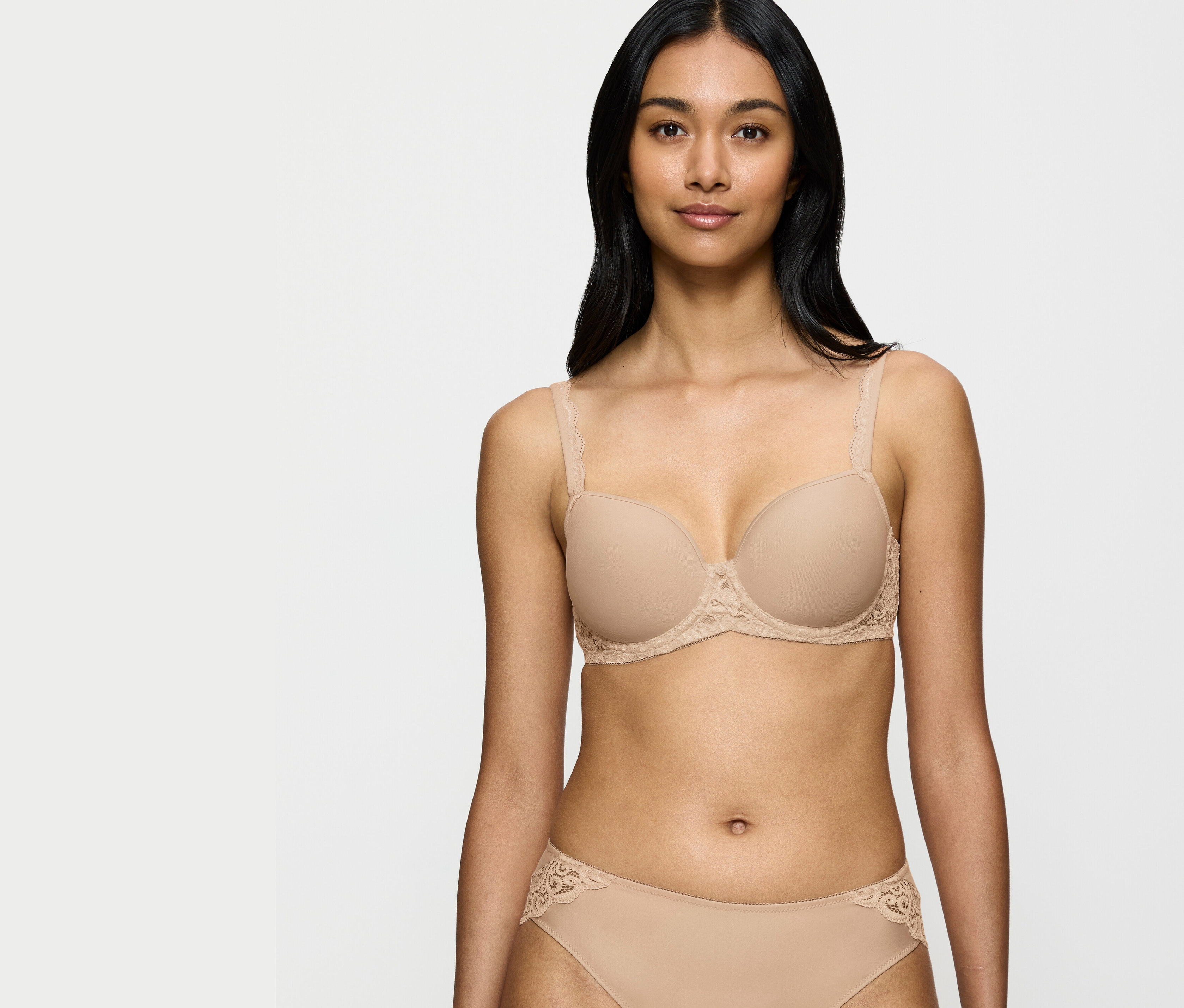 Nő visel bézs melltartót és csipkés részletekkel díszített bugyit.