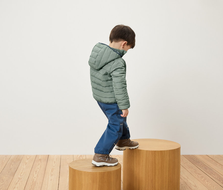 Fiú zöld kabátban és kék nadrágban faemelvényre lép.