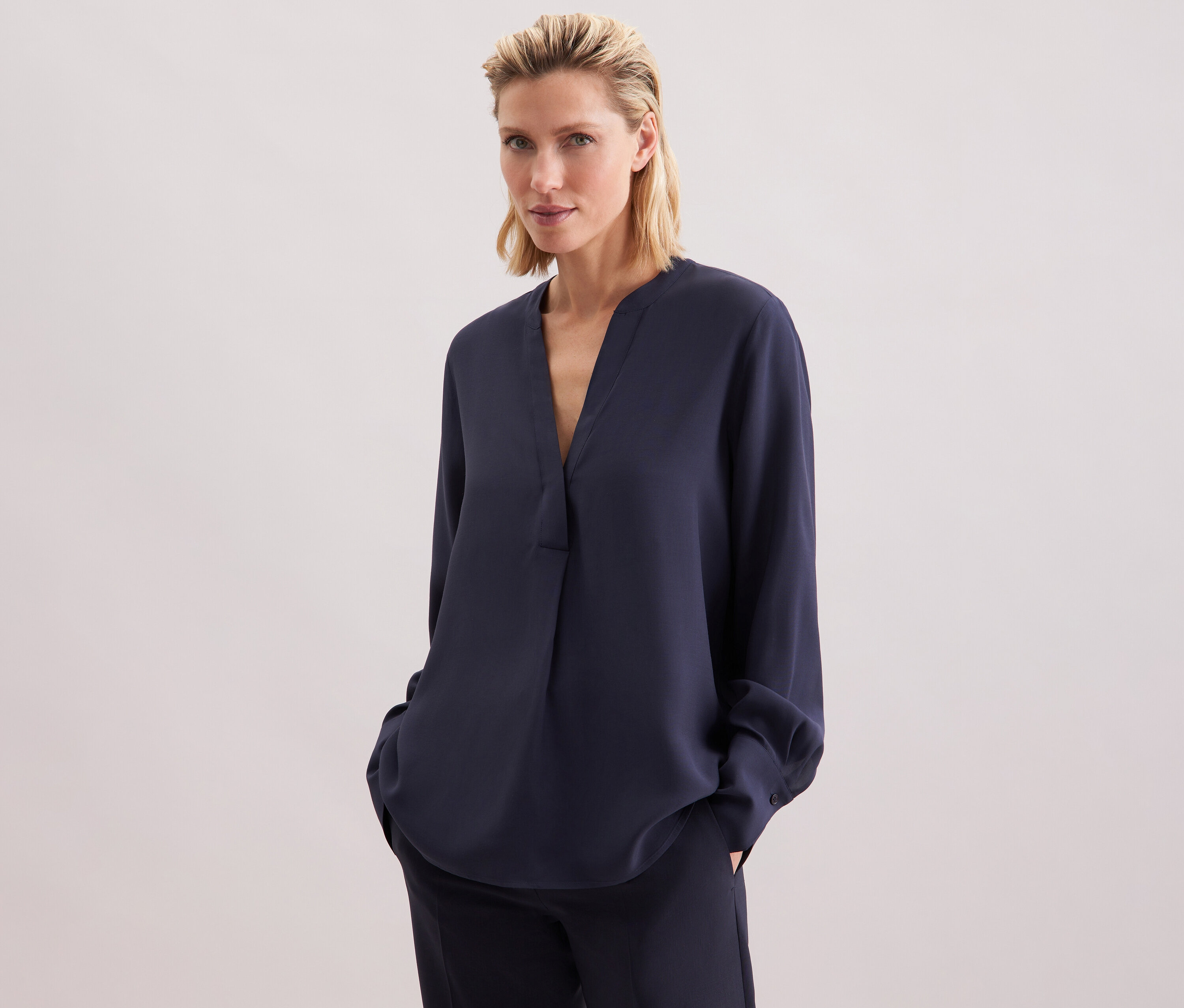 Nő visel egy tengerészkék Seidensticker viszkóz tunikát és nadrágot.