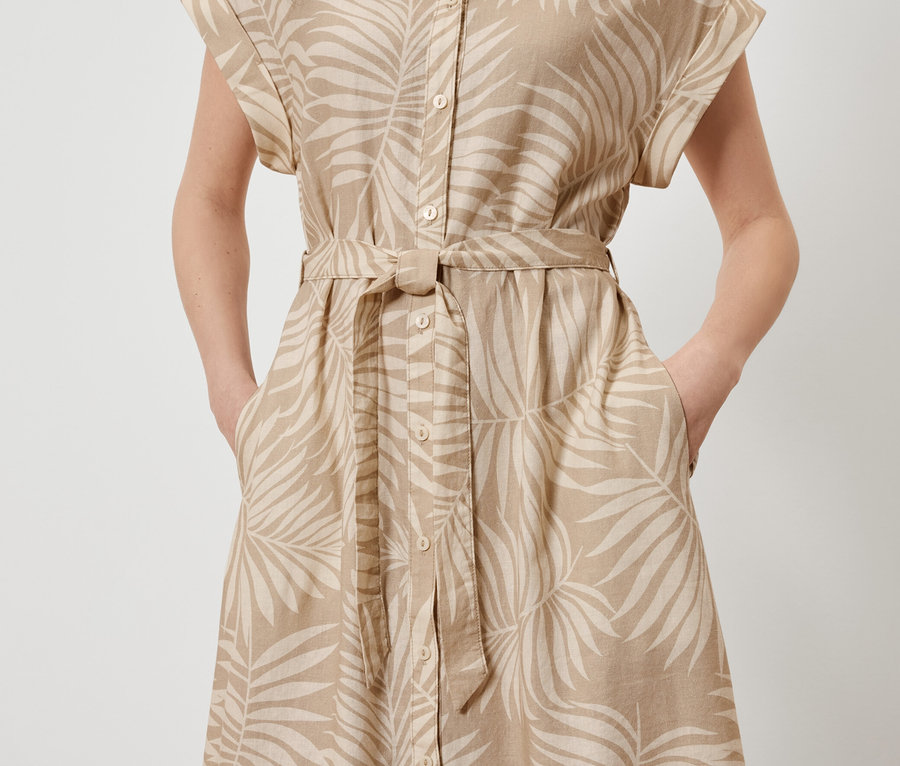 Nő pózol egy nyomott mintás lenvászon ruhában, kezével a zsebében.