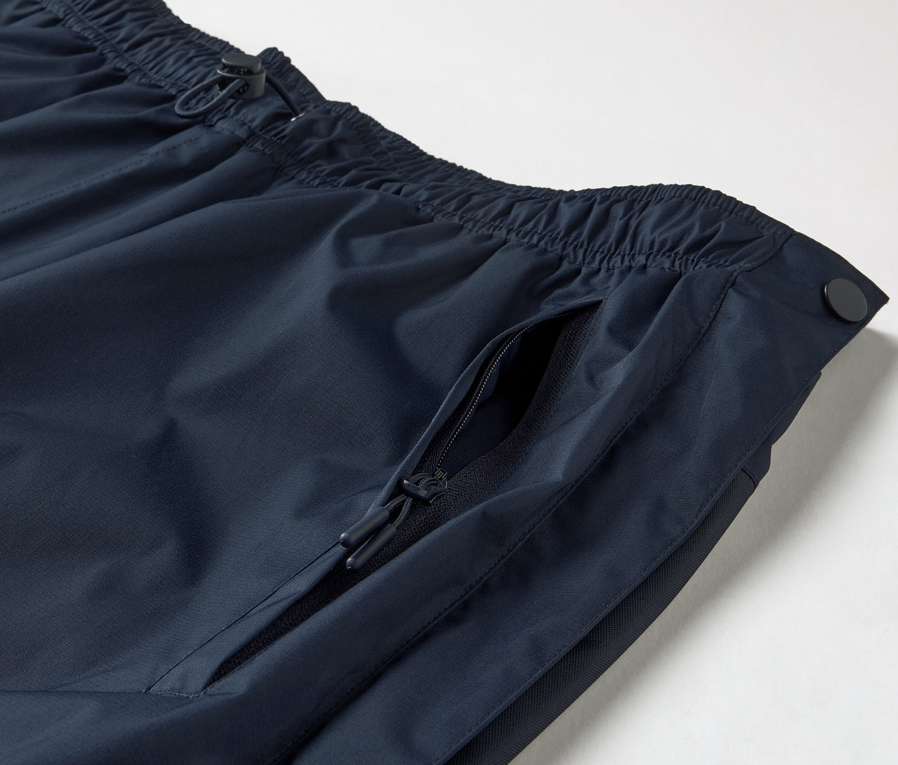 Egy high-tech esőnadrág részlete, végig cipzárral, melyen látható a húzózsinóros, rugalmas derékrész és egy cipzáras zseb.