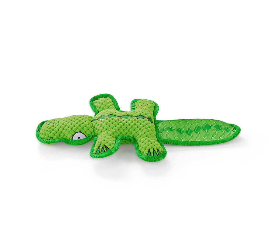 Egy zöld krokodil alakú plüss kutyajáték fekszik egy fehér háttéren.